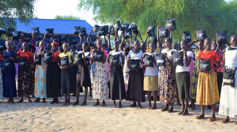 CH1835659 Women in Juba stand holding education packs